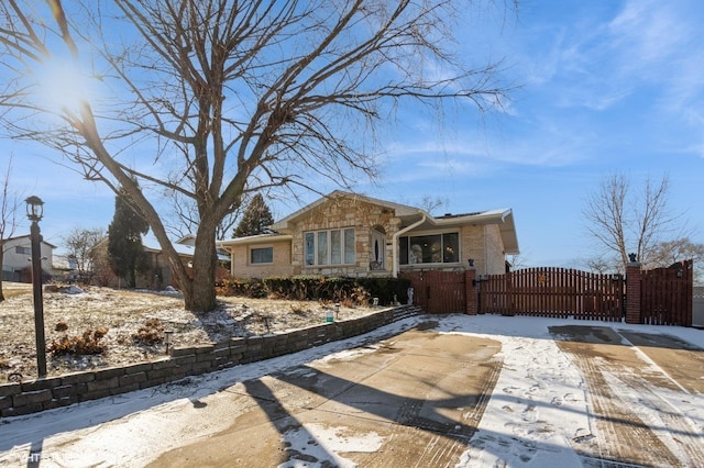 view of front of house featuring stone siding, brick siding, fence, and a gate