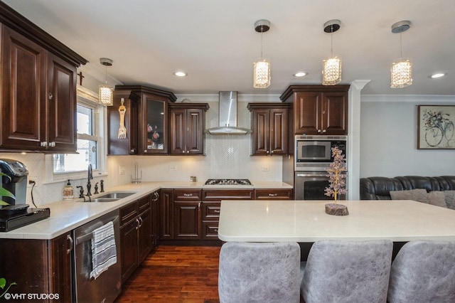 kitchen with a sink, light countertops, appliances with stainless steel finishes, dark brown cabinets, and wall chimney exhaust hood