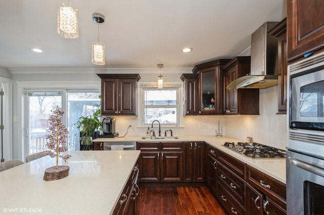 kitchen featuring stainless steel appliances, dark wood-type flooring, a sink, light countertops, and wall chimney exhaust hood