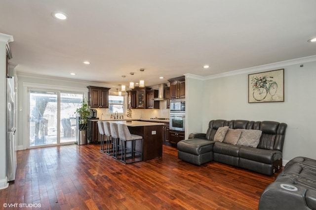 living room featuring dark wood-type flooring, recessed lighting, and ornamental molding