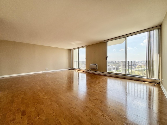 empty room with baseboards, floor to ceiling windows, wood finished floors, and a baseboard radiator