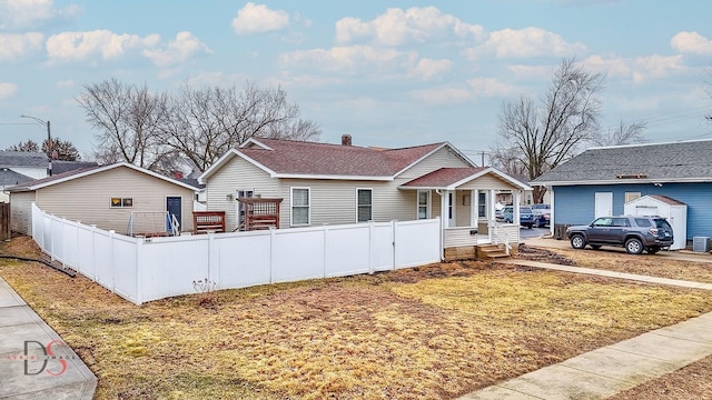 view of front of property with covered porch, a shingled roof, fence, a chimney, and a front yard