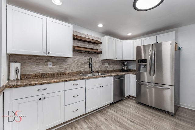 kitchen with dark countertops, appliances with stainless steel finishes, white cabinetry, open shelves, and a sink