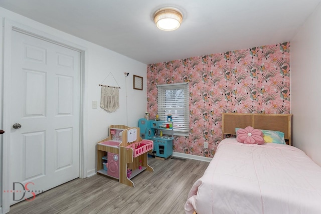 bedroom featuring wallpapered walls, baseboards, and wood finished floors