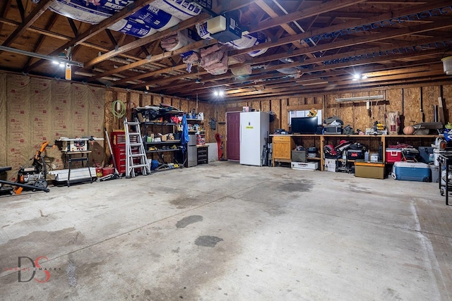 garage featuring a workshop area, freestanding refrigerator, and a garage door opener