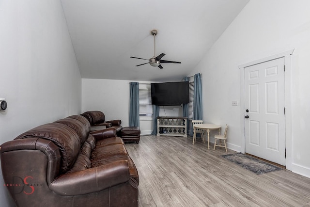 living area featuring vaulted ceiling, light wood finished floors, a ceiling fan, and baseboards