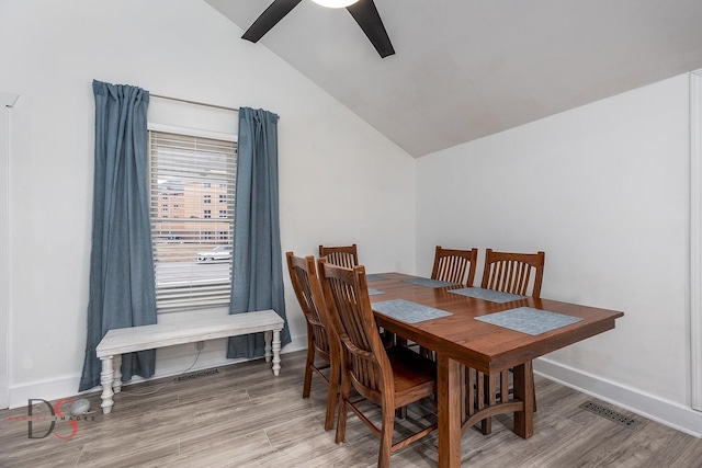 dining room with ceiling fan, light wood-style flooring, visible vents, baseboards, and vaulted ceiling