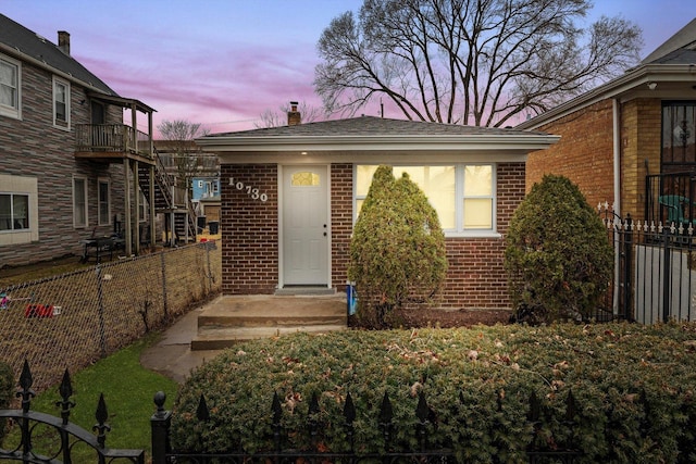 view of front of property featuring brick siding, a chimney, and fence