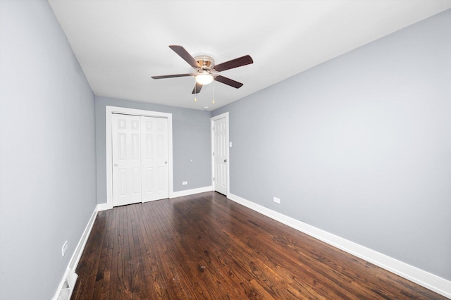 unfurnished bedroom featuring ceiling fan, dark wood-style flooring, a closet, and baseboards