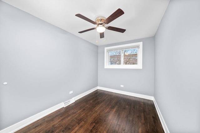 empty room with dark wood-style floors, visible vents, baseboards, and a ceiling fan