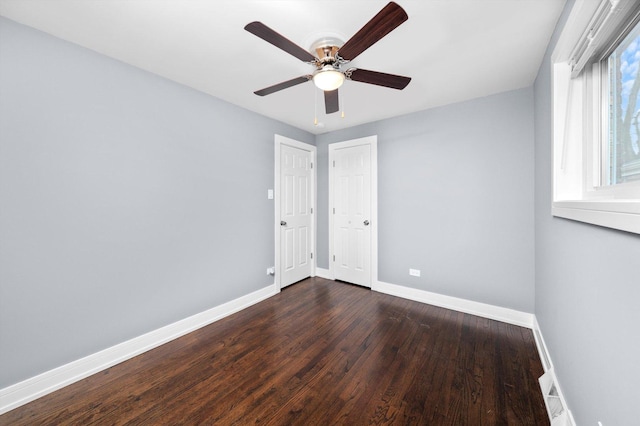 spare room featuring ceiling fan, dark wood finished floors, and baseboards