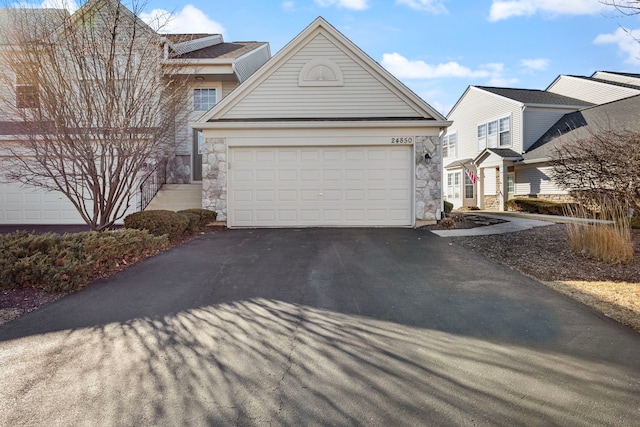 view of front of house with a garage, stone siding, and driveway