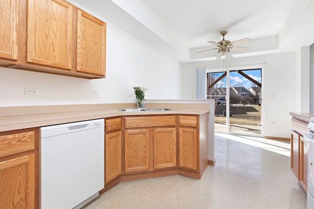 kitchen with ceiling fan, dishwasher, a peninsula, a raised ceiling, and a sink