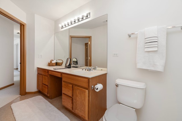 bathroom with toilet, vanity, and baseboards