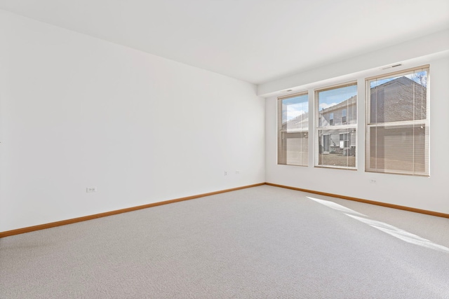 unfurnished room with visible vents, light colored carpet, and baseboards