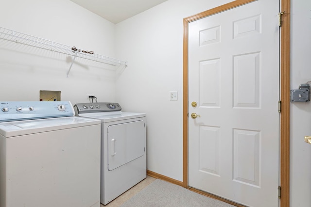 clothes washing area featuring laundry area, baseboards, and washer and clothes dryer