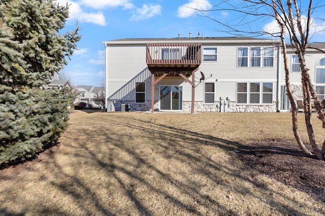 rear view of property featuring stone siding, central AC, and a yard