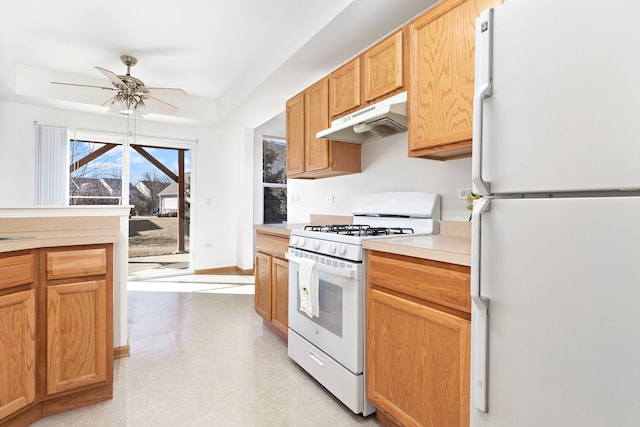 kitchen featuring baseboards, ceiling fan, under cabinet range hood, light countertops, and white appliances