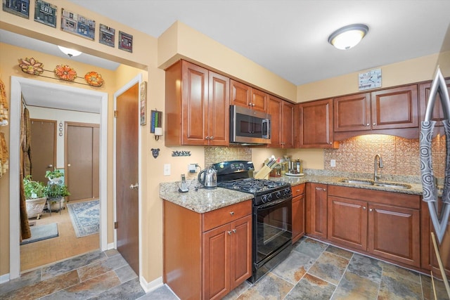 kitchen featuring appliances with stainless steel finishes, decorative backsplash, a sink, and stone tile floors