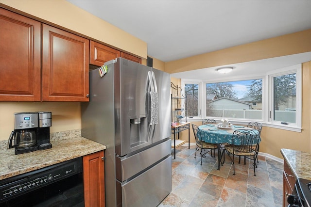 kitchen featuring light stone counters, black dishwasher, stainless steel fridge with ice dispenser, stove, and baseboards