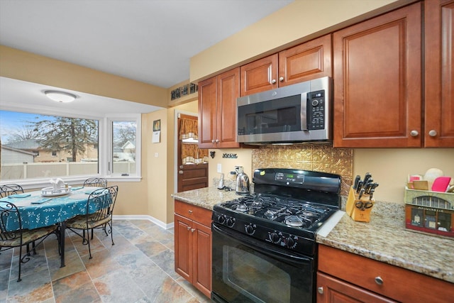 kitchen with light stone counters, stainless steel microwave, backsplash, gas stove, and baseboards