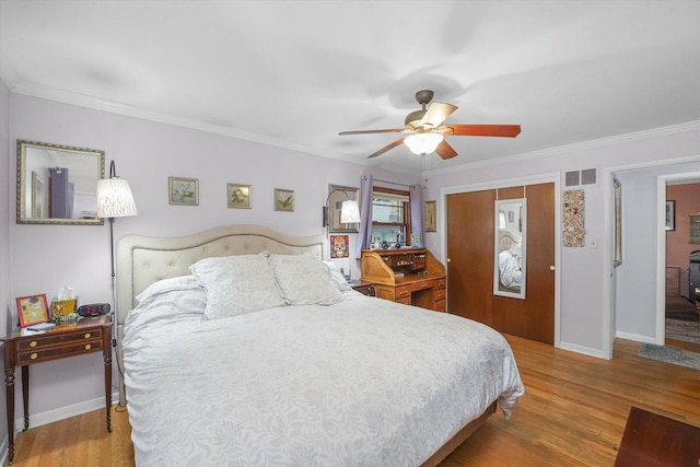 bedroom with ornamental molding, wood finished floors, visible vents, and baseboards