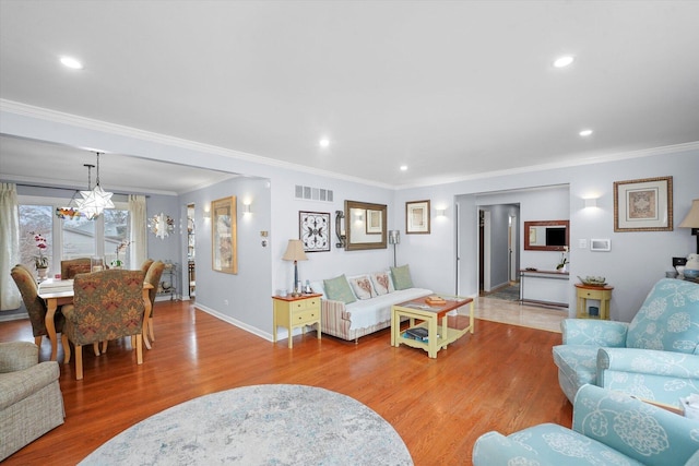 living area with crown molding, visible vents, and wood finished floors