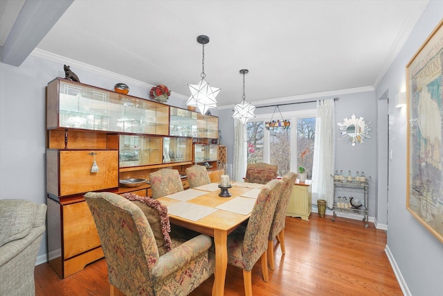 dining room with baseboards, light wood-type flooring, and crown molding