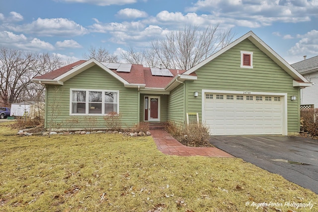 single story home featuring a garage, solar panels, aphalt driveway, roof with shingles, and a front yard