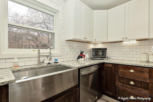 kitchen featuring white cabinets, dishwasher, backsplash, and a sink