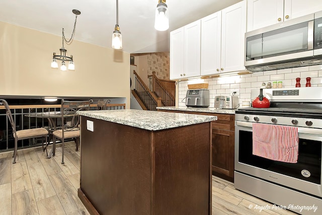 kitchen featuring appliances with stainless steel finishes, light wood-style floors, white cabinetry, and a kitchen island