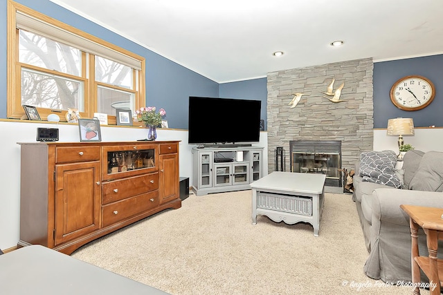 living area with ornamental molding, light colored carpet, and a stone fireplace