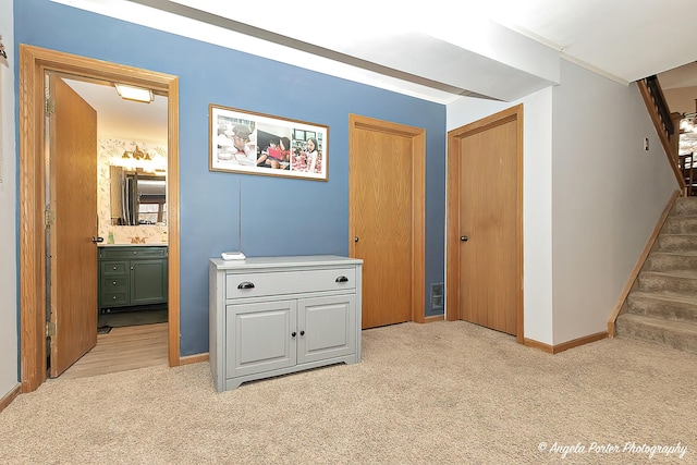 hall with light carpet, a sink, stairway, and baseboards