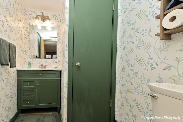 bathroom featuring wallpapered walls, baseboards, and vanity