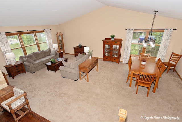 living area featuring light carpet, vaulted ceiling, an inviting chandelier, and baseboards