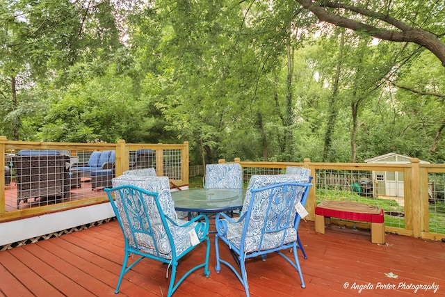 wooden deck featuring outdoor dining area and a wooded view