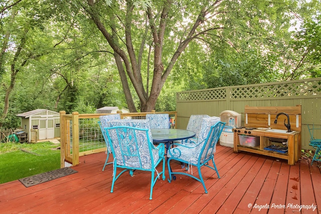 wooden terrace with an outbuilding, outdoor dining area, and a shed