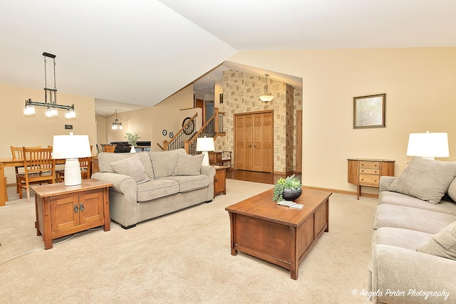 living area featuring baseboards, light colored carpet, lofted ceiling, stairway, and an inviting chandelier