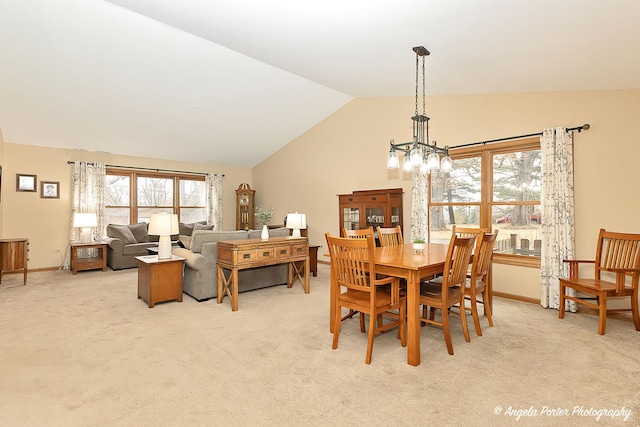 dining space with a chandelier, lofted ceiling, light colored carpet, and baseboards