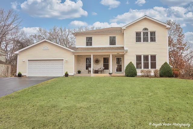 traditional-style home with a front lawn, driveway, an attached garage, and a porch