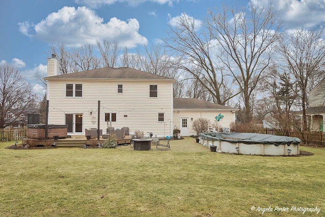 back of house featuring a fire pit, a covered pool, fence, and a wooden deck