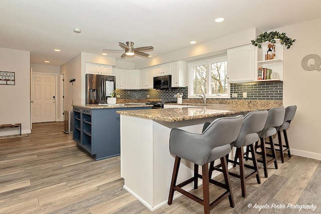 kitchen with black microwave, open shelves, a peninsula, and stainless steel fridge with ice dispenser