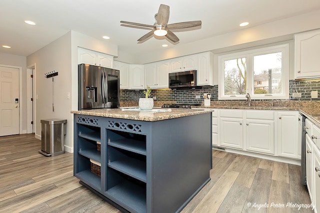 kitchen with open shelves, light stone countertops, stainless steel appliances, and light wood finished floors