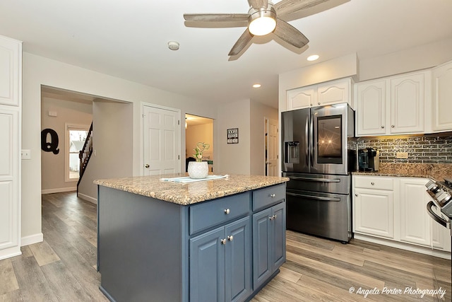 kitchen featuring stainless steel appliances, a kitchen island, white cabinets, blue cabinetry, and tasteful backsplash