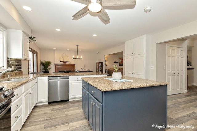 kitchen featuring stove, a peninsula, blue cabinetry, white cabinetry, and a sink