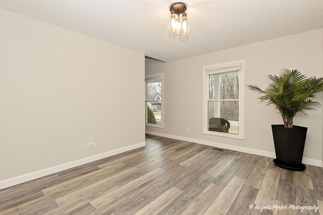 unfurnished room featuring light wood-style floors, visible vents, and baseboards