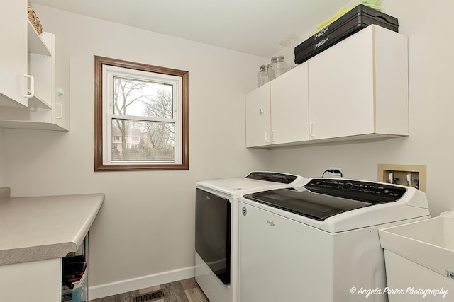 laundry room featuring cabinet space, baseboards, visible vents, washer and clothes dryer, and a sink