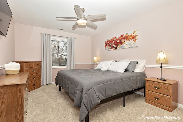 bedroom featuring light carpet, baseboards, visible vents, and a ceiling fan