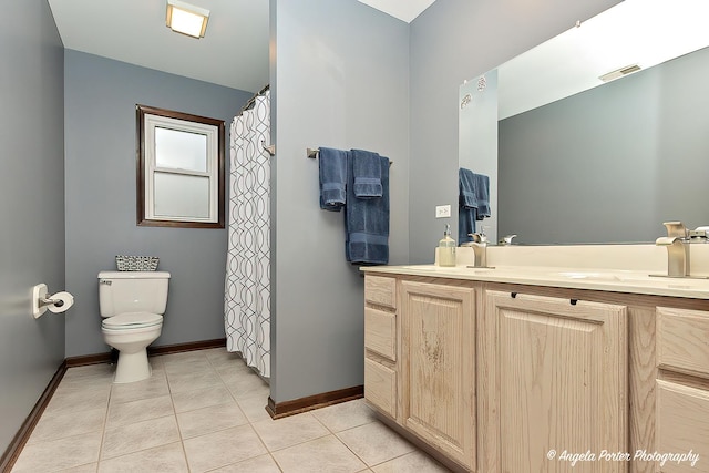 bathroom featuring visible vents, toilet, a sink, baseboards, and tile patterned floors