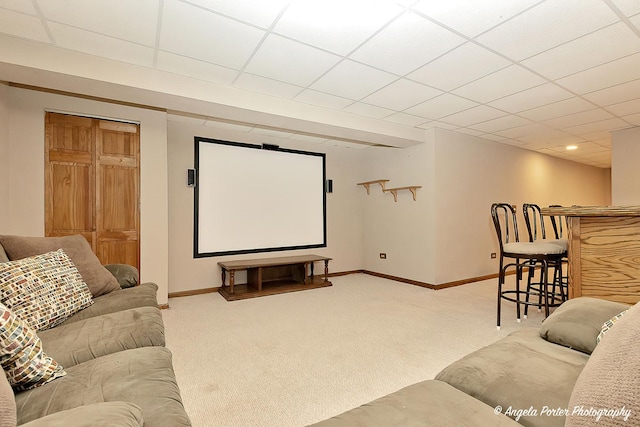 home theater room with baseboards, a drop ceiling, and light colored carpet